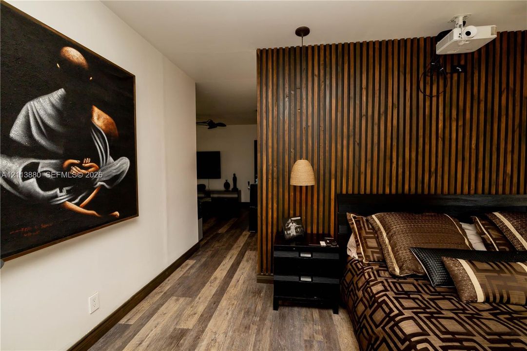 Vertical wood slat accent wall featuring a hanging pendant light and multi-toned wood-finish flooring