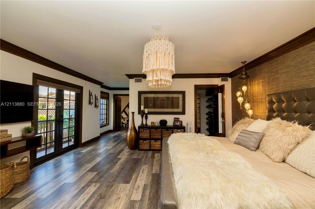 Wood-finish flooring, dark wood-trimmed doorways and windows, integrated French doors, and a textured accent wall