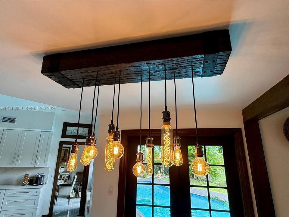 Custom industrial-style light fixture featuring a rustic reclaimed wood beam housing and a multi-pendant arrangement with exposed filament bulbs