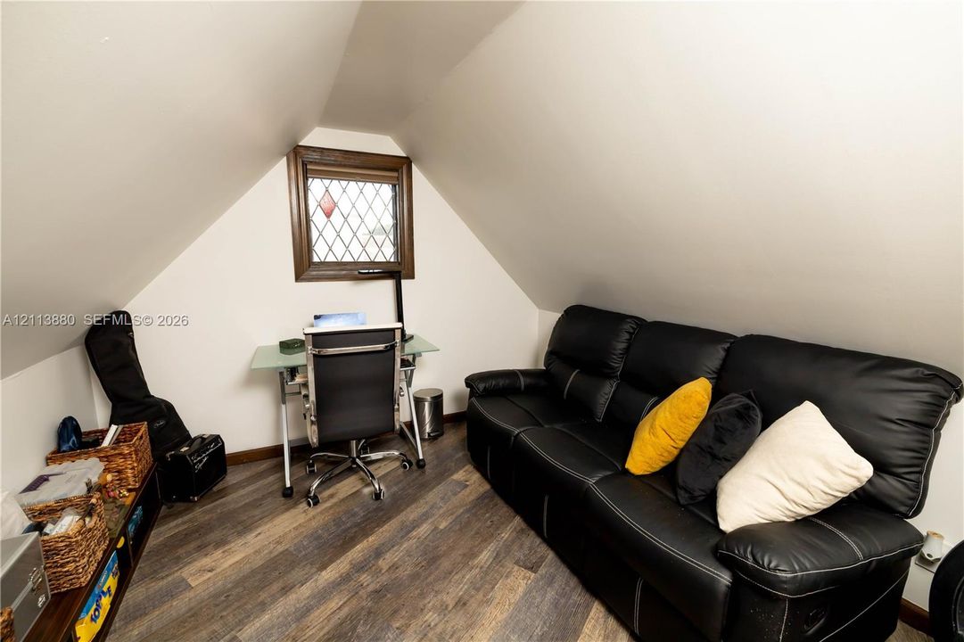 Vaulted ceiling, wood-finish flooring, and a leaded glass window with wood trim