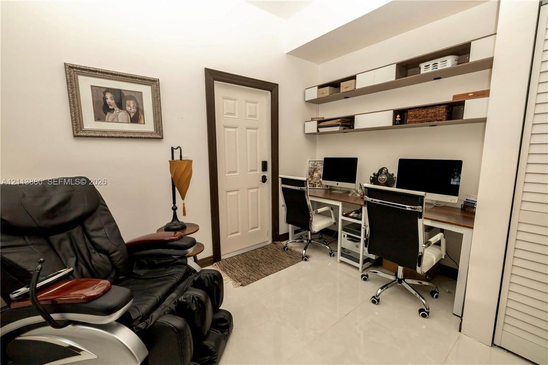 Built-in dual-level shelving with storage compartments, tile flooring, and solid-core paneled entry door with dark finish trim