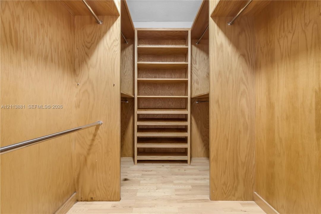 Walk-in closet featuring custom wood-finished cabinetry, integrated shelving, tiered storage drawers, and metal clothing rods