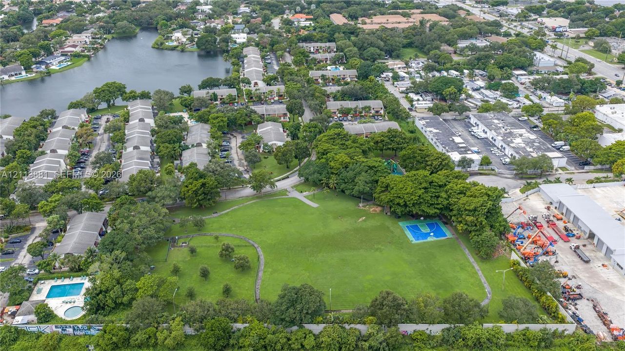 Aerial perspective featuring expansive green space, a basketball court, swimming pool, and mature trees