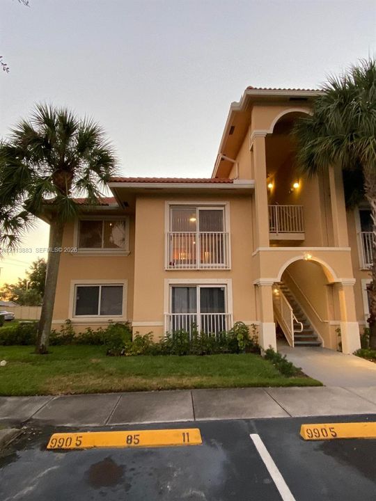 Multi-level exterior featuring tan stucco siding, a tiled roof, arched architectural detailing, and private balconies with vertical railings