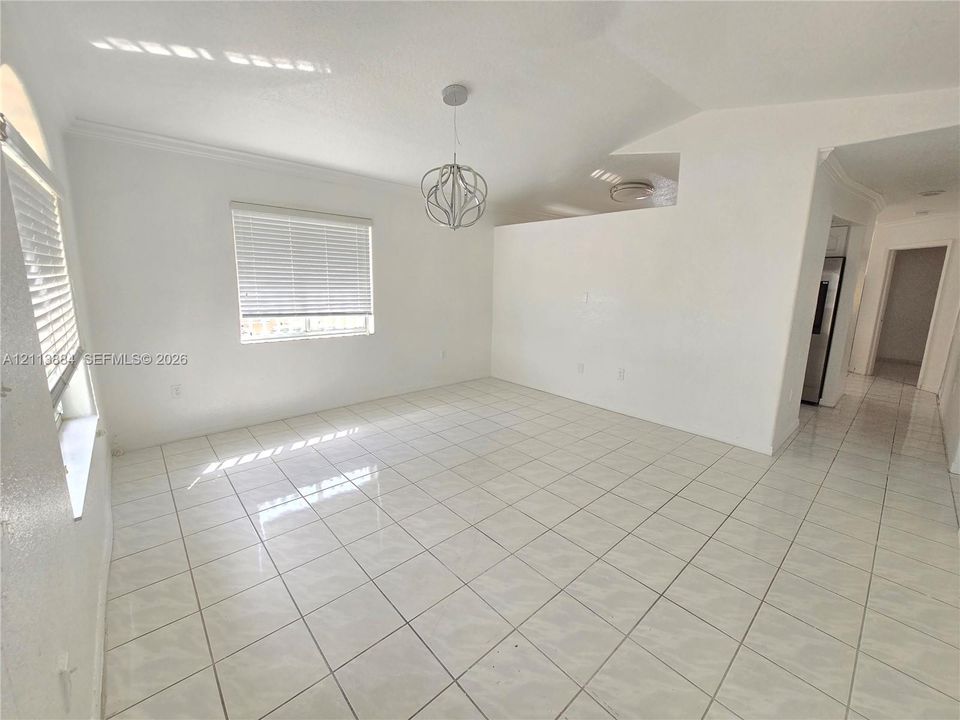 Open-concept room featuring light tile flooring, high vaulted ceilings, architectural archway accents, and a contemporary spherical pendant light fixture