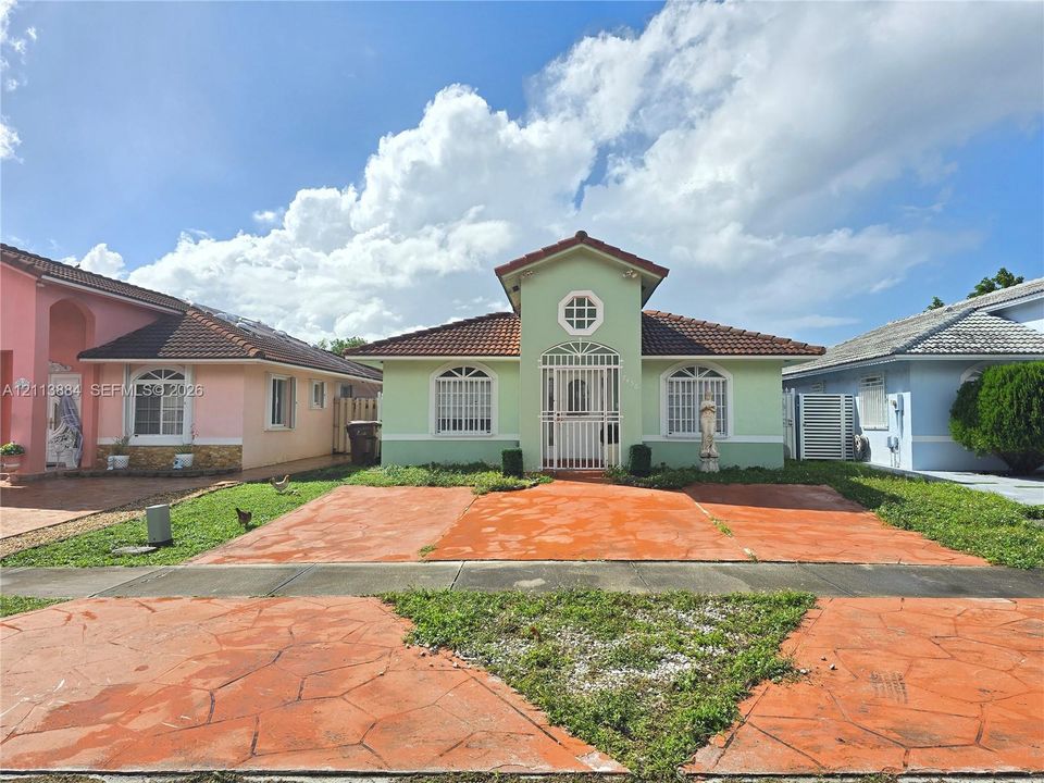 Single-story residence featuring a tile roof, arched window detailing, an octagonal accent window, and an integrated metal security gate entry