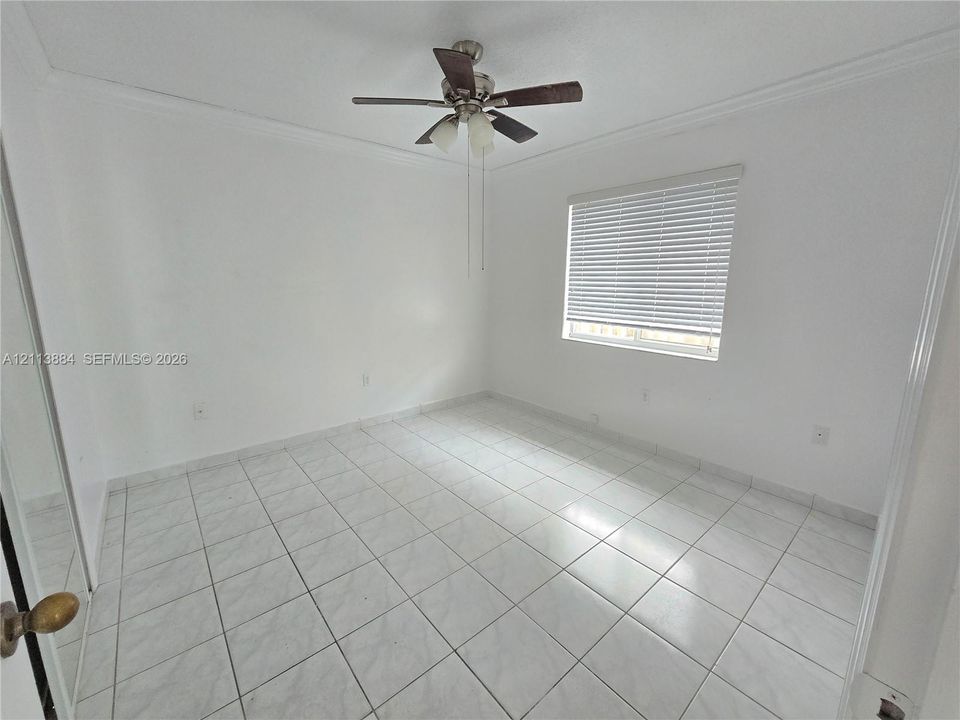 Neutral-toned tile flooring, ceiling fan with integrated lighting, and horizontal window blinds