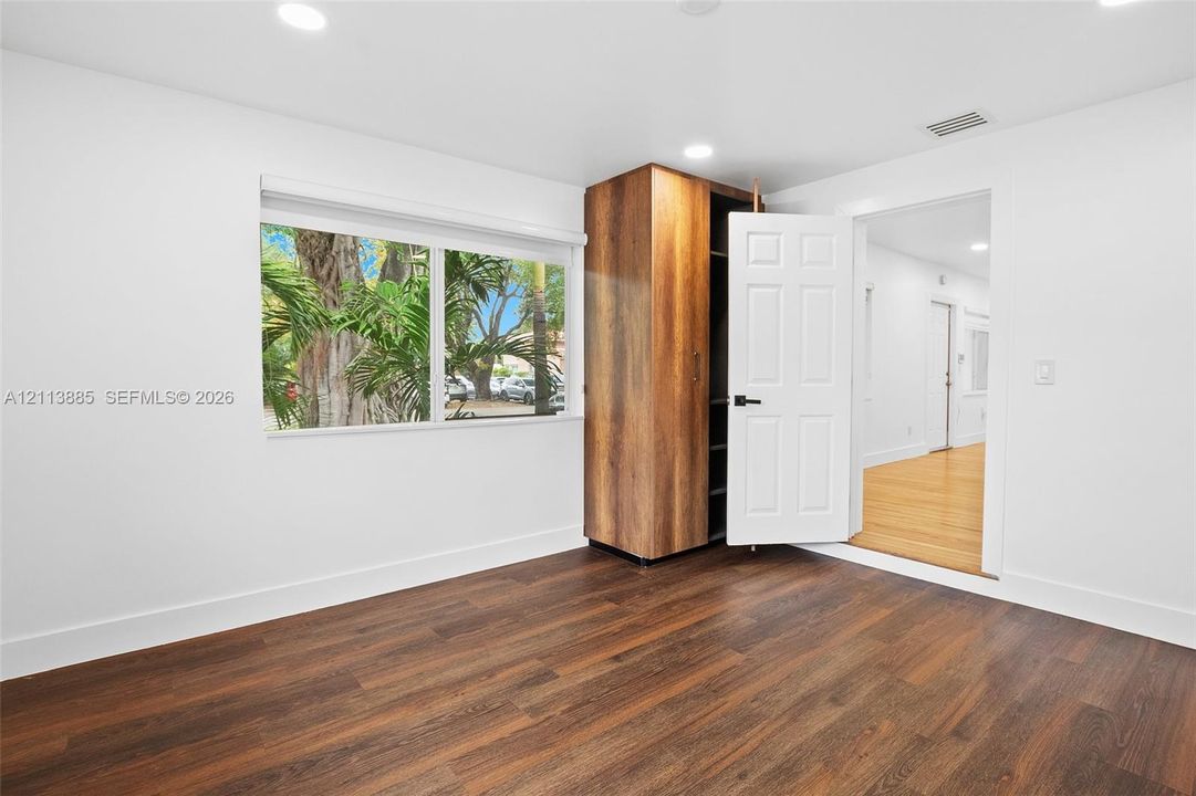 Wood-finish flooring, recessed lighting, expansive window with exterior greenery, and built-in wood-finish cabinetry