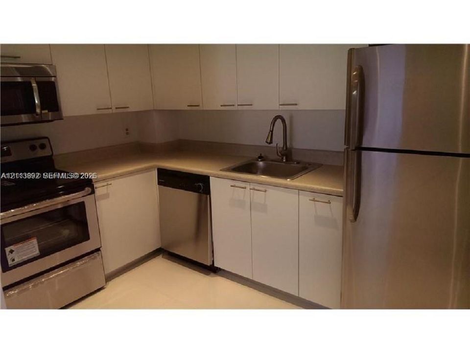 Kitchen featuring white cabinetry, stainless steel appliances, a pull-down faucet, and neutral countertops