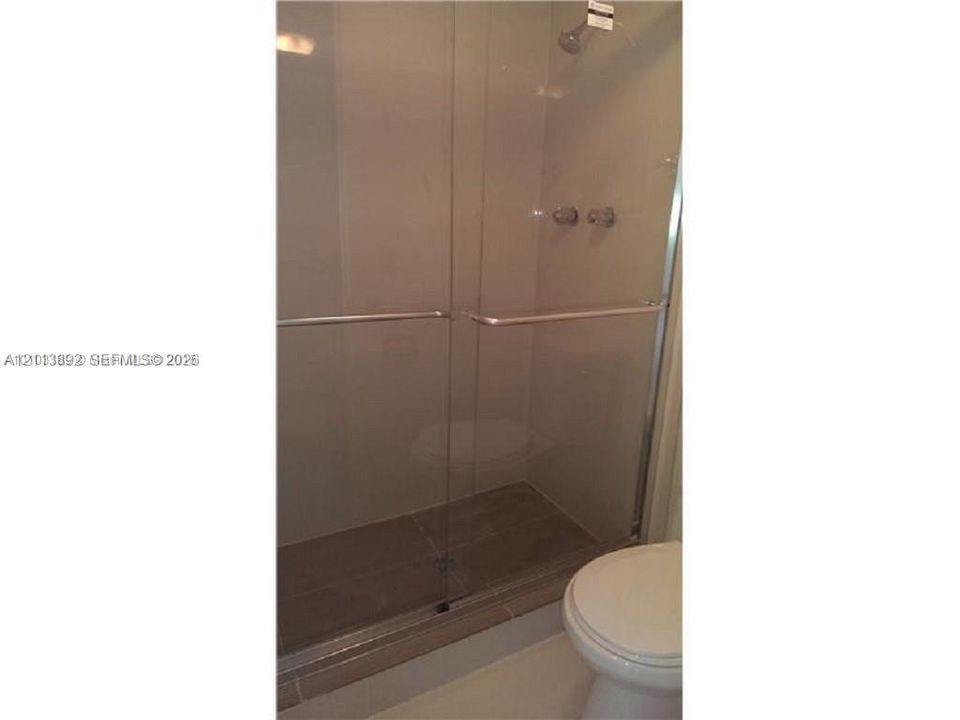 Walk-in shower featuring a glass-panel enclosure, metallic hardware, and neutral-toned wall tiling