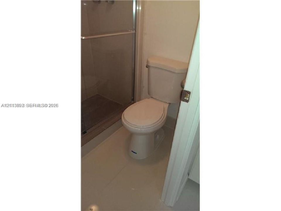 Enclosed shower with glass sliding doors and tile flooring, paired with a standard-profile toilet