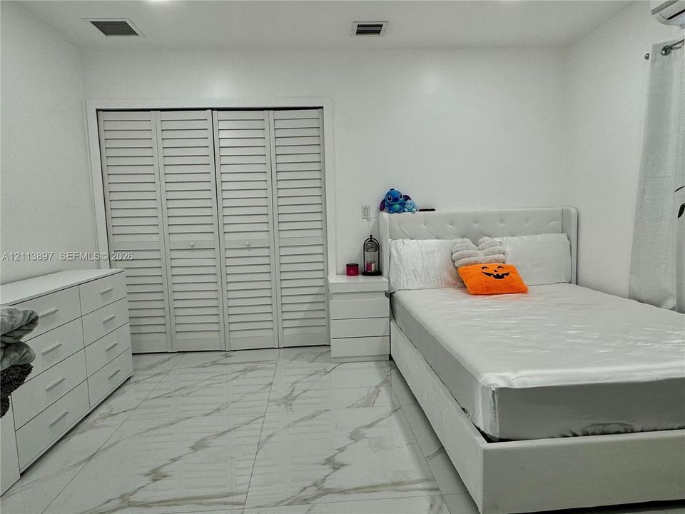 Large-format tile flooring featuring a neutral veined pattern and white louvered-style closet doors