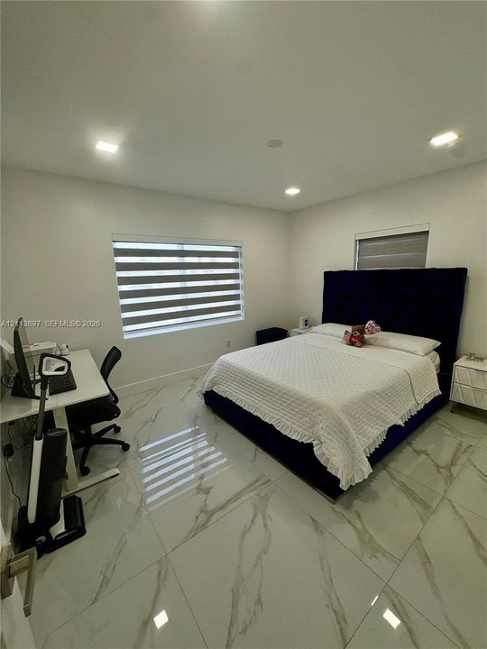 Large-format tile flooring with vein detailing, recessed ceiling lighting, and windows featuring integrated dual-layered roller shades