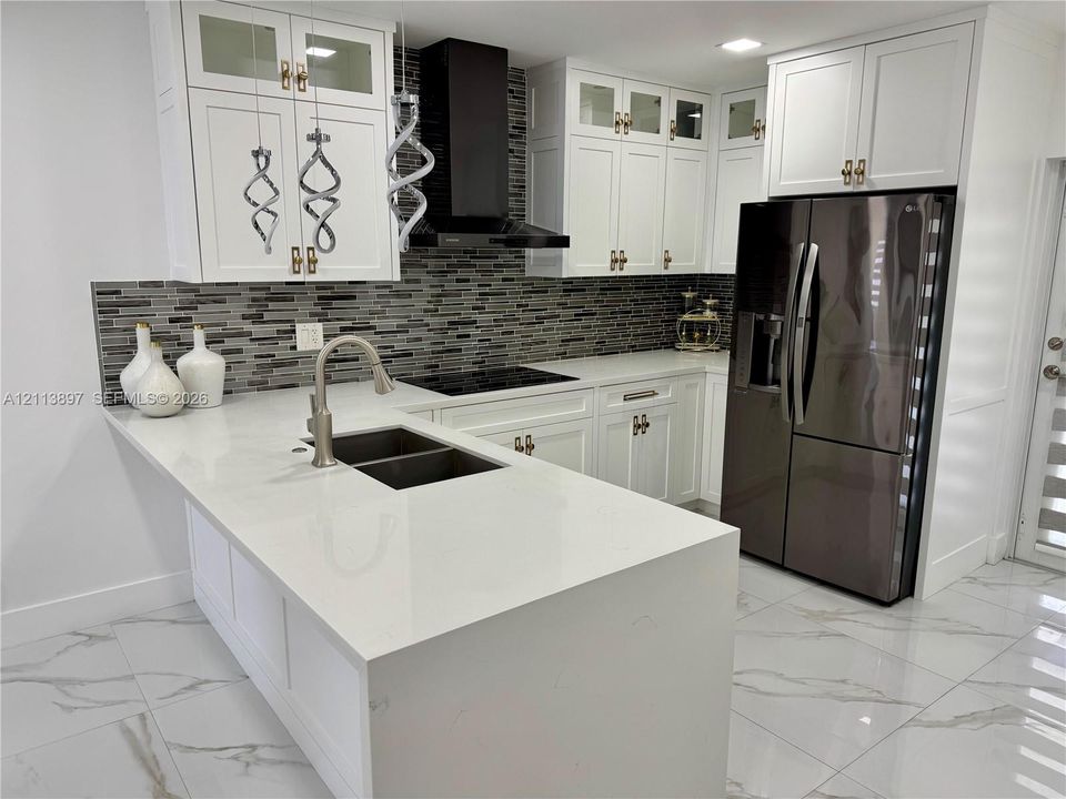 Kitchen featuring white cabinetry, quartz countertops, a mosaic tile backsplash, a stainless steel undermount sink with a gooseneck faucet, and large-format tile flooring