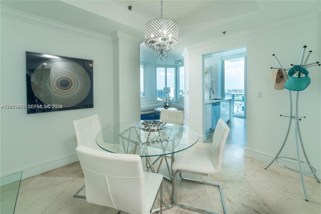 Dining area featuring polished stone tile flooring, crown molding, and a tiered crystal chandelier