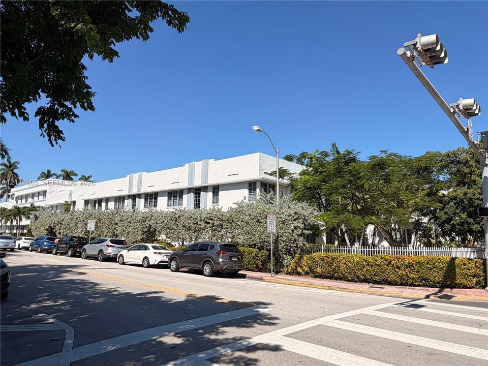 Low-rise exterior featuring a stucco facade, flat roofline, vertical architectural accents, and mature perimeter landscaping