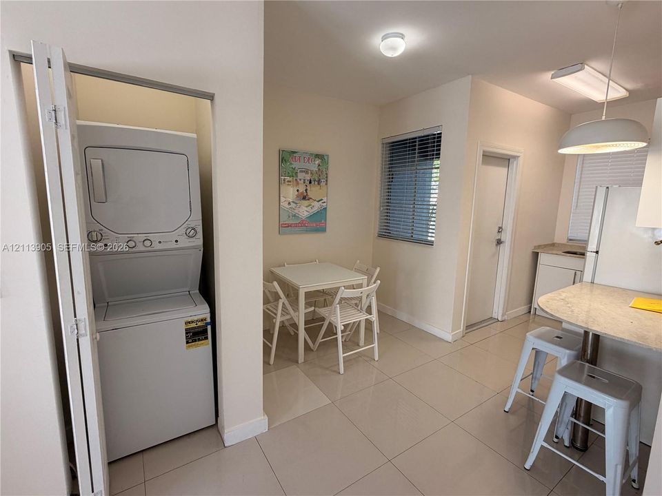 Stackable laundry appliance, tile flooring, breakfast bar with stone-finish countertop, and recessed ceiling lighting