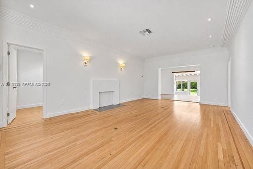 Living area featuring wood-finish flooring, a decorative fireplace, recessed ceiling lighting, wall-mounted sconces, and crown molding