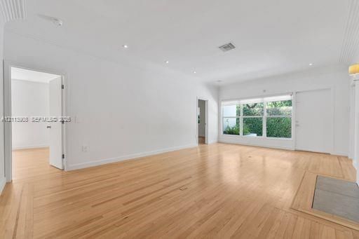 Open-concept living space featuring wood-finish flooring, recessed lighting, and large windows with integrated blinds