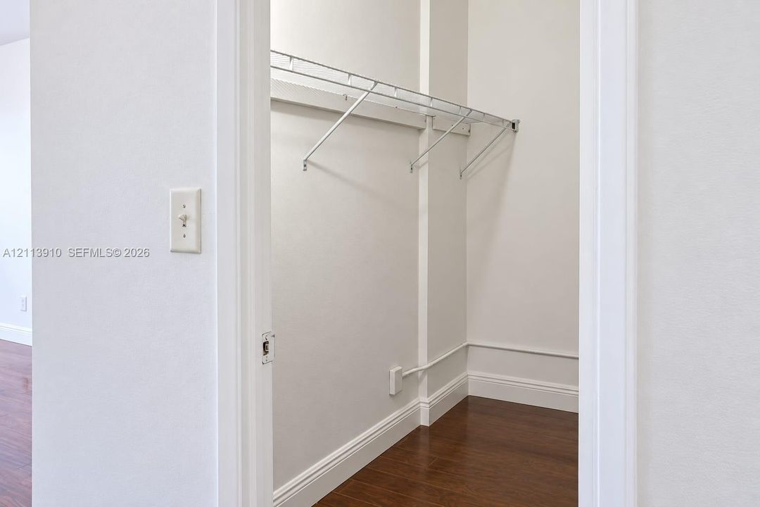 Storage closet featuring wood-finish flooring and integrated metal shelving