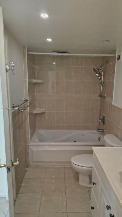 Bathroom featuring a combination bathtub and shower with beige wall tiling, recessed lighting, ceramic floor tile, and a white vanity