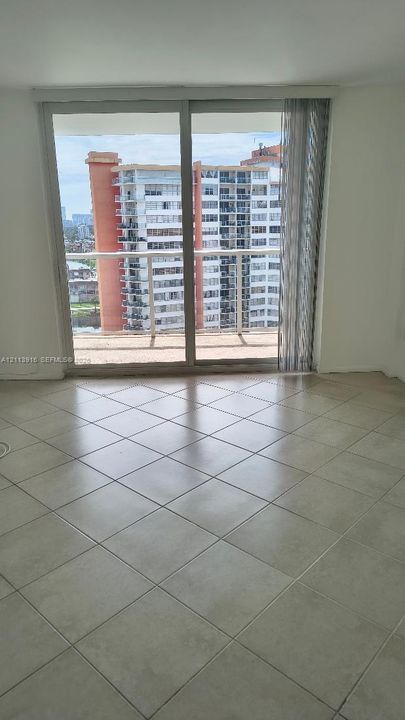 Large-format tile flooring, floor-to-ceiling sliding glass doors, and a private balcony with horizontal railings