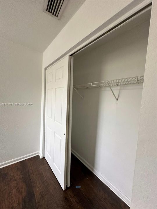 Closet featuring six-panel sliding doors and built-in wire shelving, finished with wood-finish flooring