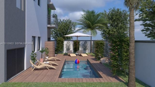 Private outdoor space featuring a rectangular in-ground pool, wood-finish decking, perimeter privacy wall, and mature landscaping