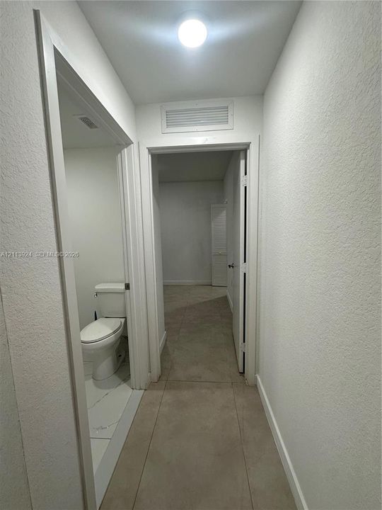 Neutral-toned tile flooring, flush-mount ceiling lighting, and a white two-piece toilet
