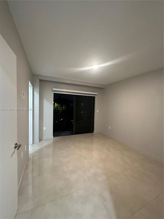 Room featuring large-format tile flooring, neutral wall tones, and a sliding glass door providing external access