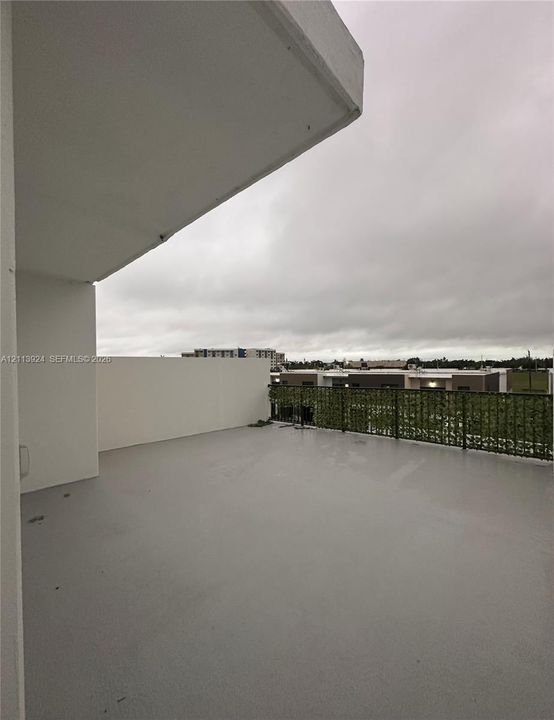 Covered balcony featuring smooth-surface flooring, high solid-panel perimeter walls, and a decorative screen railing