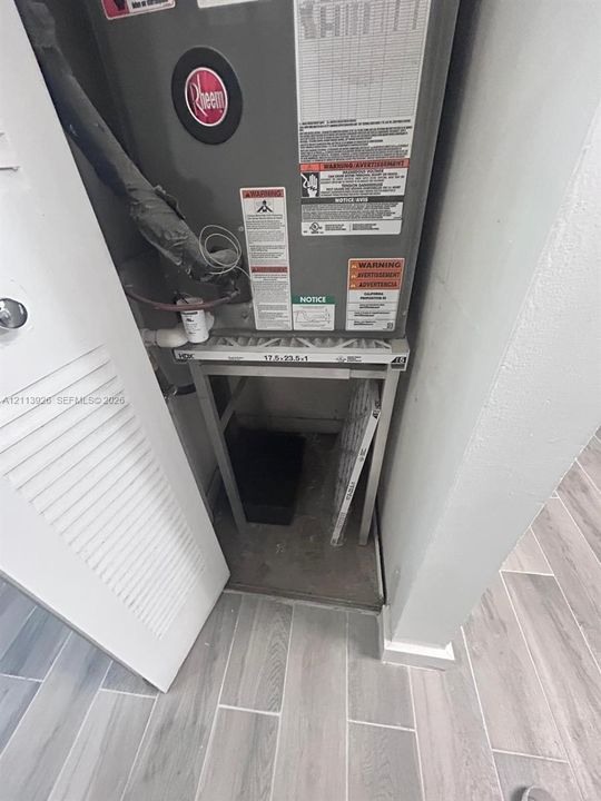 Heating and cooling unit housed in a dedicated closet with louvered door access and wood-finish tile flooring