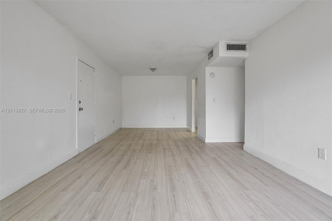 Open-concept interior featuring light-toned wood-finish flooring and neutral wall paint