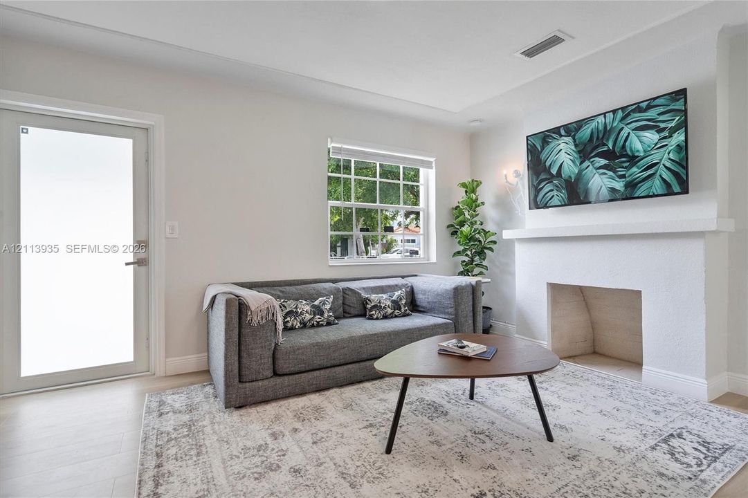 Living area featuring a masonry fireplace with a classic mantel, glass-paned exterior door, multi-lite window, and light-toned flooring