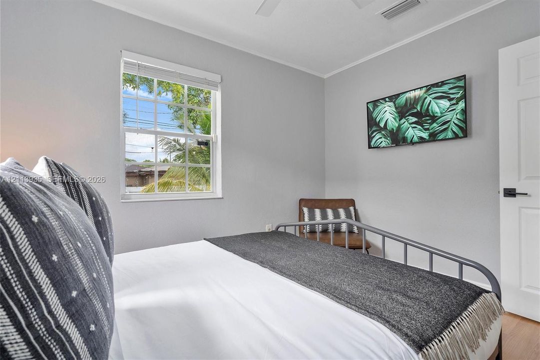 Room featuring neutral paint, double-hung muntin window, white six-panel door with matte black hardware, wood-finish flooring, and a ceiling fan