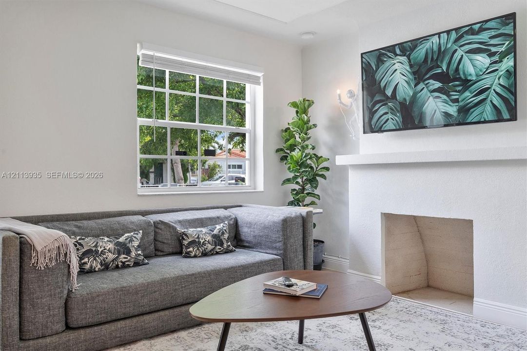 Fireplace with a minimalist mantel, grid-pattern window, and wall-mounted lighting fixture