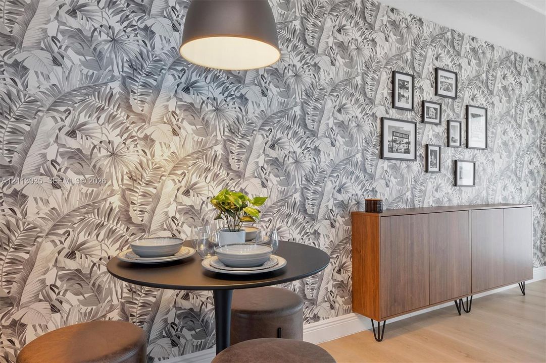 Botanical-print feature wallpaper, custom built-in wood-finish cabinetry, wide-plank wood-finish flooring, and a dome-style pendant light fixture