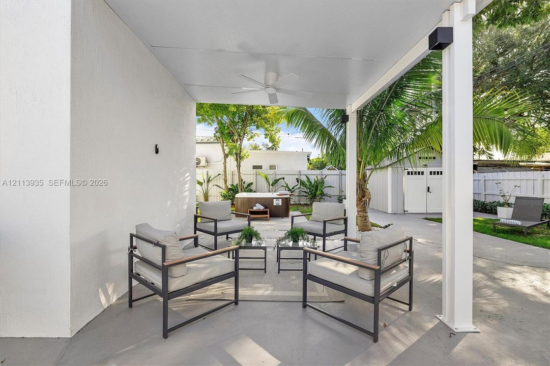 Covered patio featuring a painted concrete floor, a ceiling-mounted fan, and a built-in spa