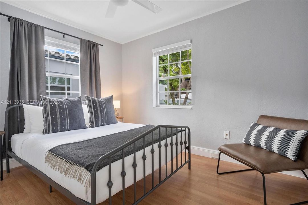Room featuring wood-finish flooring, dual windows with muntin detailing, and a ceiling fan