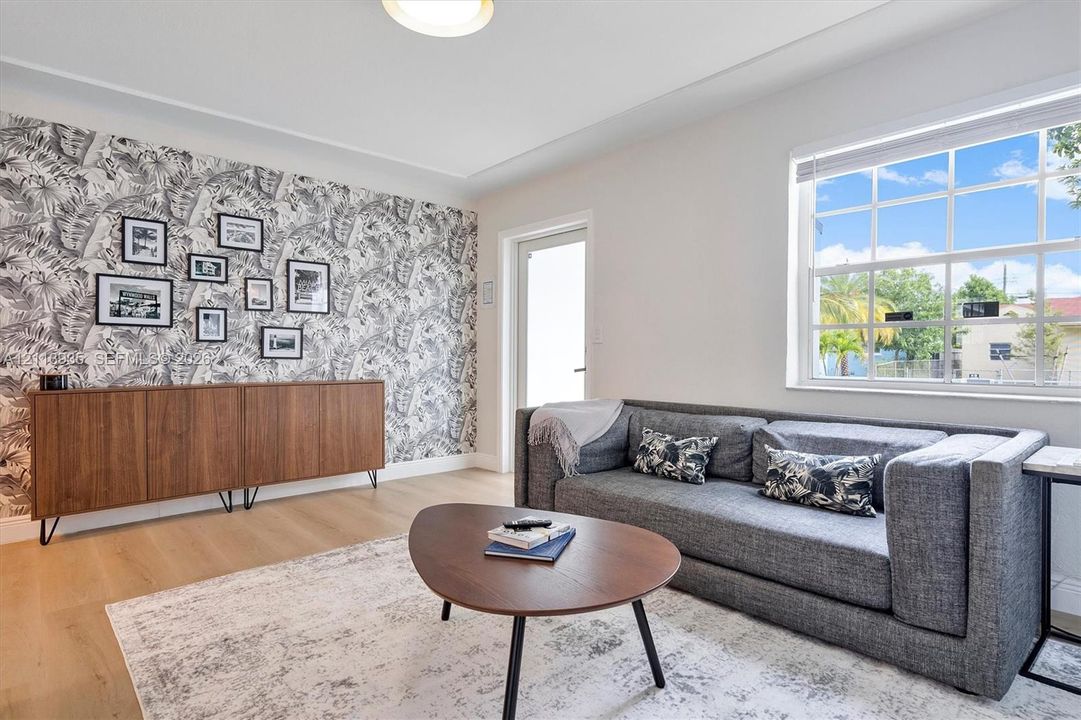 Interior space featuring wood-finish flooring, a decorative patterned accent wall, and a multi-pane window