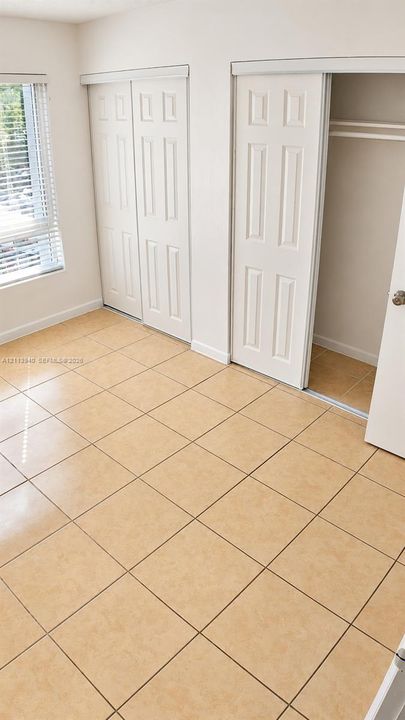 Ceramic tile flooring, multi-panel sliding closet doors, and horizontal slat window blinds