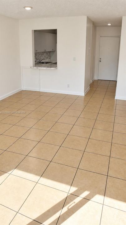 Ceramic tile flooring, pass-through opening, stone-finish countertop, recessed lighting, and solid-core entry door