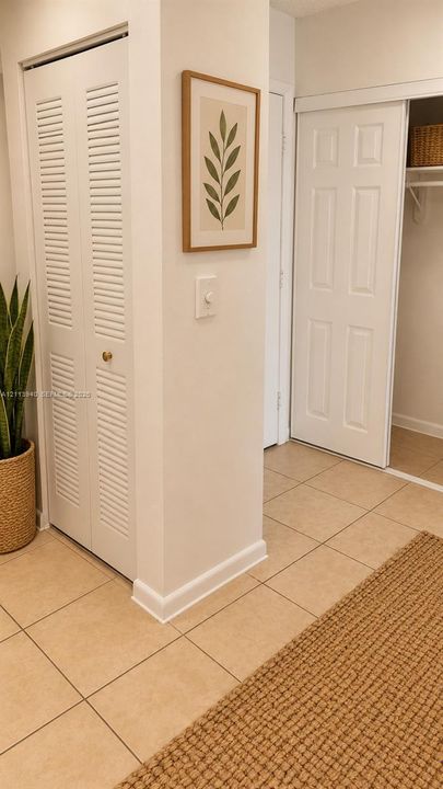 Ceramic tile flooring, bi-fold louvered closet doors, and a sliding closet door with built-in shelving