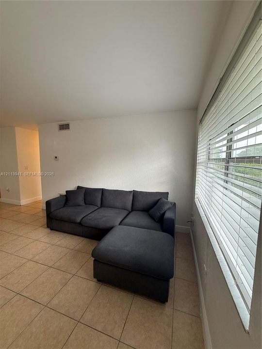 Ceramic tile flooring, neutral wall finishes, and expansive windows featuring horizontal slat blinds