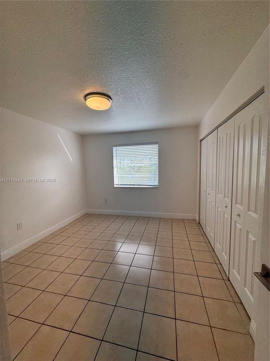 Tile flooring, multi-panel sliding closet doors, and flush-mount ceiling lighting