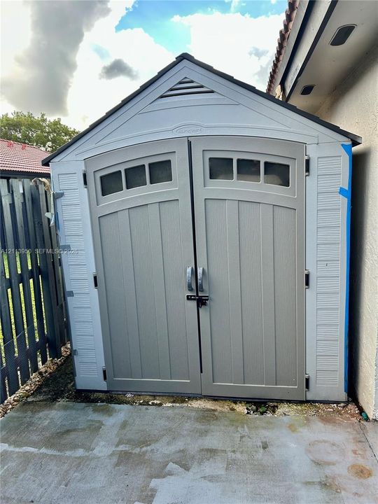 Outdoor storage structure featuring a gable roof, double doors with integrated window panels, and a low-maintenance composite exterior
