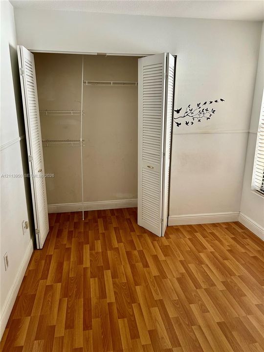 Wood-finish flooring, white louvered closet doors, and interior wire shelving