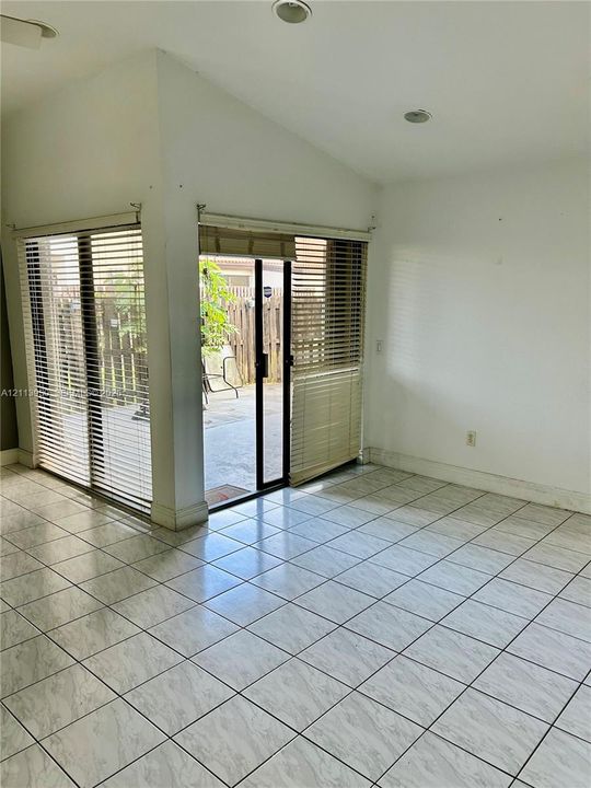 Ceramic tile flooring, vaulted ceiling with recessed lighting, and corner sliding glass doors