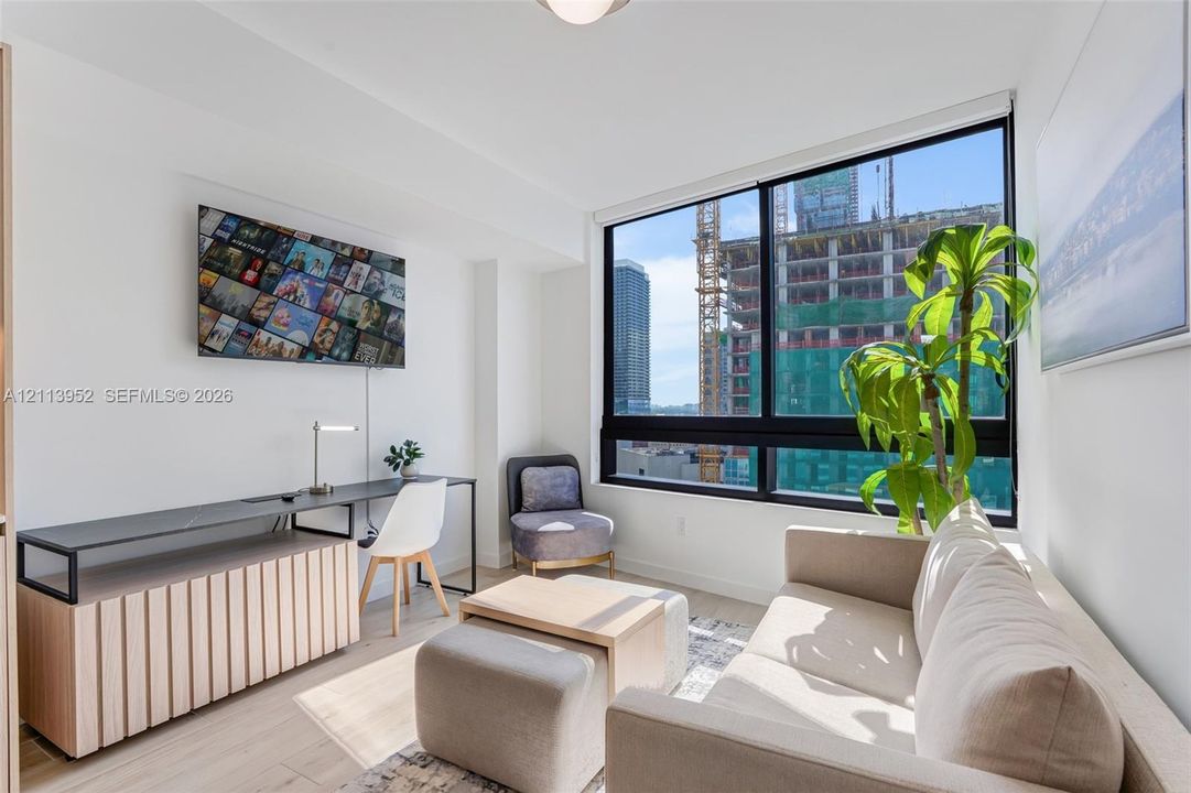Floor-to-ceiling windows, wood-finish flooring, and crisp white walls