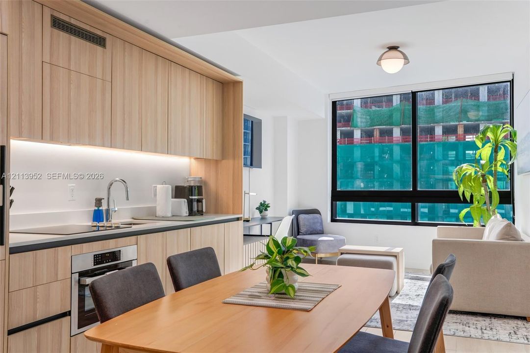 Kitchen featuring flat-panel wood-finish cabinetry, integrated appliances, under-cabinet lighting, and large windows with black frames
